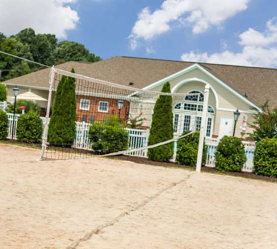 A white pillar stands in front of a house with a brown roof.