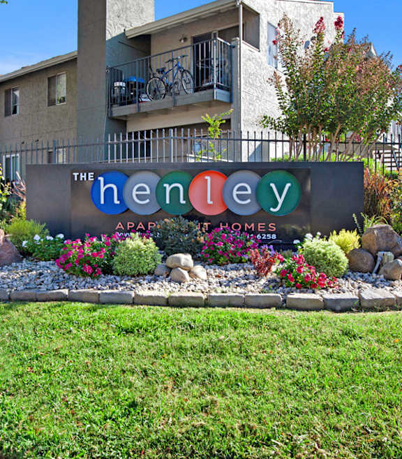 A sign for The Henley Apartments is surrounded by flowers and rocks at The Henley Apartments, Suisun City, CA, 94585