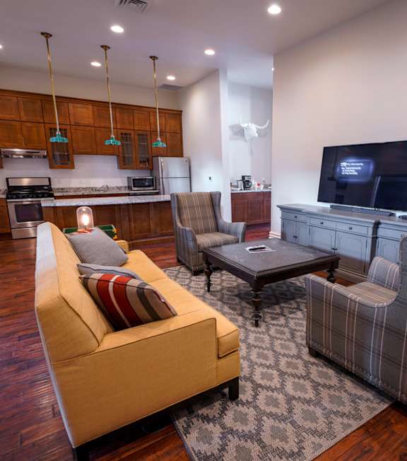 A living room with a yellow couch and a grey chair.