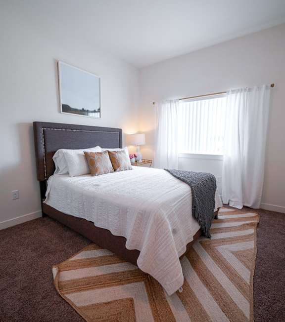 A bedroom with a large bed and striped rug.