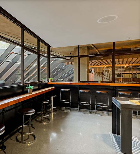 A bar with a long wooden counter and stools is shown.