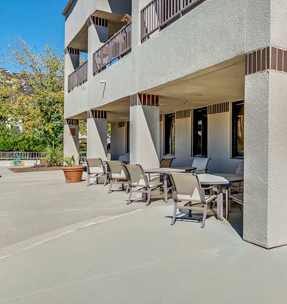A modern building with a balcony and a table and chairs outside. at Legacy Hills at Poway 55+ Apartments, Poway, California