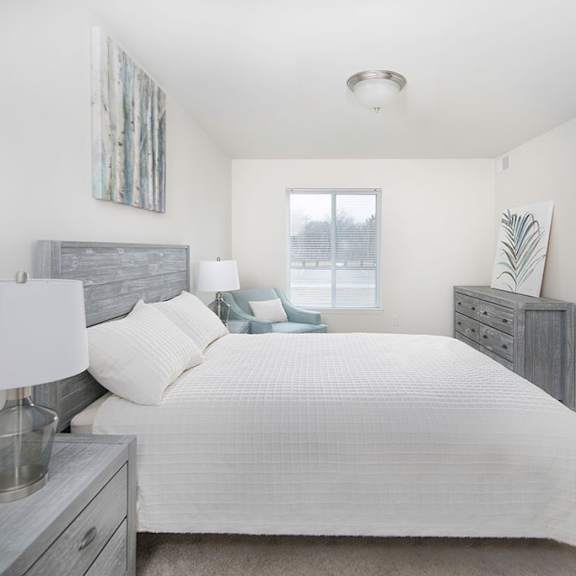 a white bedroom with a large bed and a window