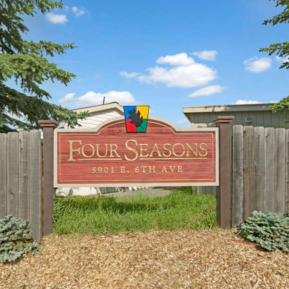 A sign for Four Seasons Apartments behind a wooden fence.