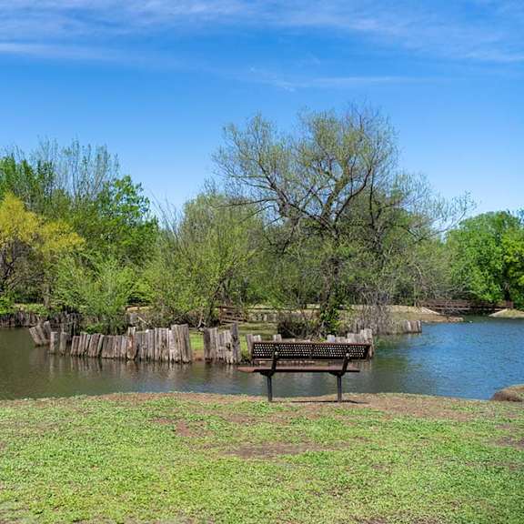 A park bench sitting next to a pond at Brookwood Village.