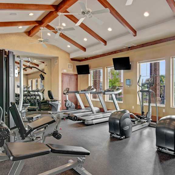A gym with treadmills and other exercise equipment and windows at Stoneleigh at the Reserve Apartment Homes. 