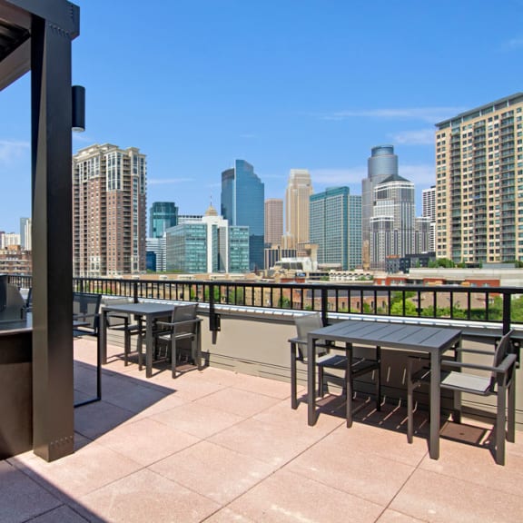 The rooftop balcony lounge with couches, chairs, coffee tables, and a grill at Gatsby Apartments. 