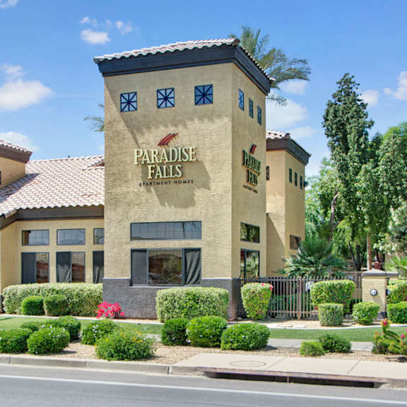 The exterior of the front office of Paradise Falls, with light tan walls and a sign 