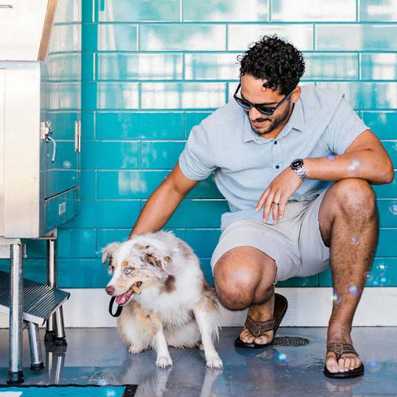 A man with a dog sitting by a pool.