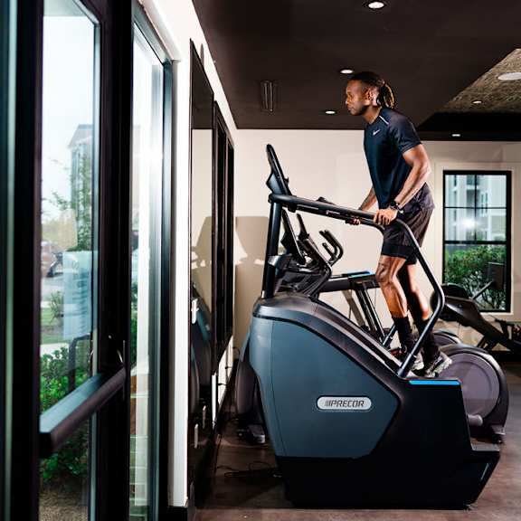 A man is working out on an exercise bike in a room with a view of the outdoors.