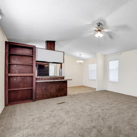an empty living room with a ceiling fan and a bookshelf at Buckingham Village in Universal City, TX