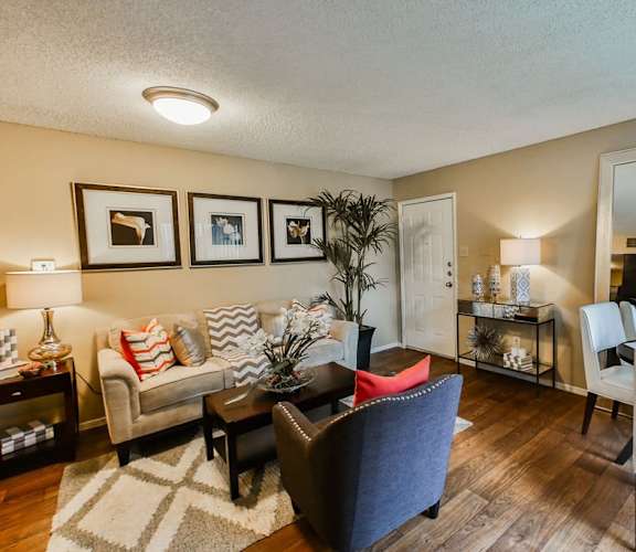a living room with a couch and a chair in front of a dining room table with a