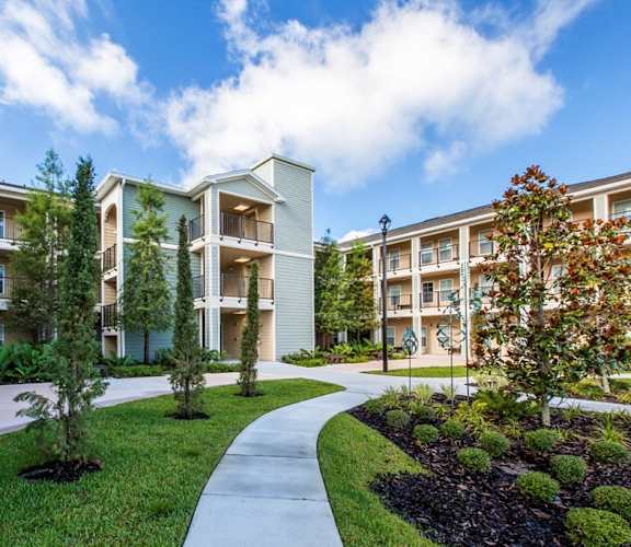 an exterior view of an apartment building with sidewalks and grass and trees