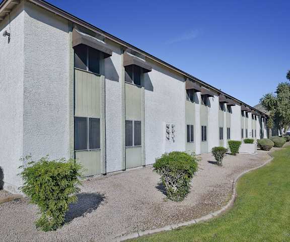 A long building with many windows and bushes in front.