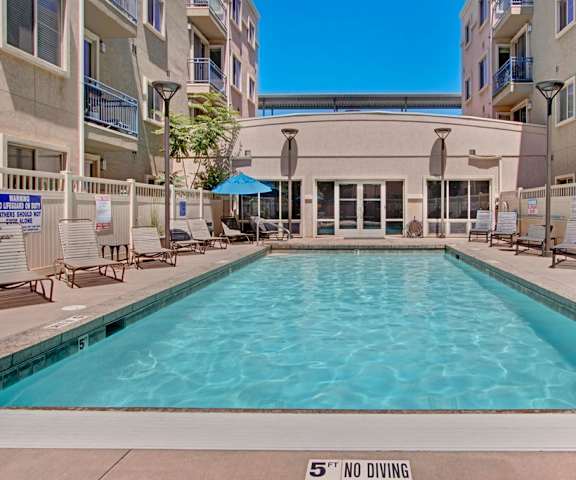 Outdoor pool surrounded by pool chairs and tables and chairs at Bridges Apartments. 