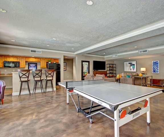 A resident lounge with a ping pong table, couch, chairs, and community kitchen at Bridges Apartments.