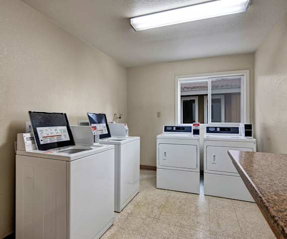 The laundry room with shelves, washers, and dryers at the Greenbriar Apartment Homes. 