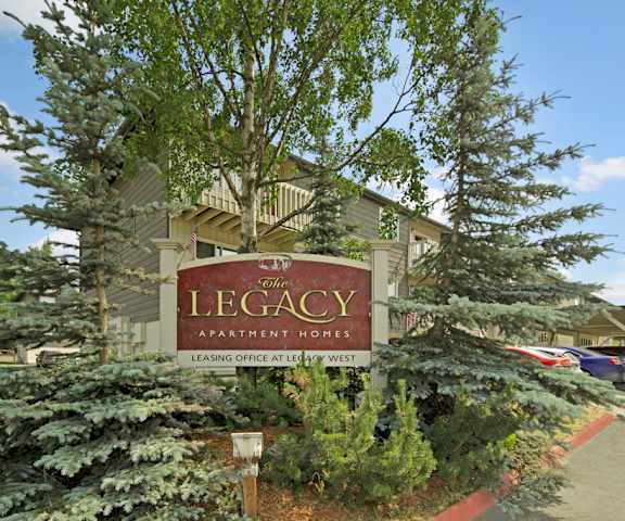 The exterior sign, building, and parking lot with trees and greenery of the Legacy Apartment Homes.