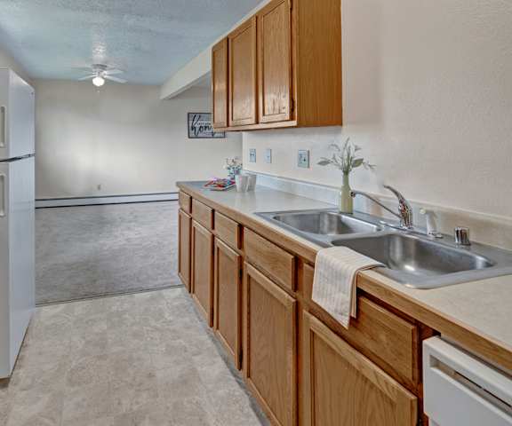 A cozy kitchen with white appliances, light counter, and spacious wooden cabinets at the Legacy Apartment Homes. 