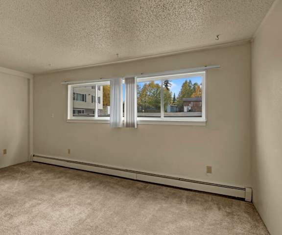 An empty carpeted bedroom with a window at Montclair Apartment Homes. 