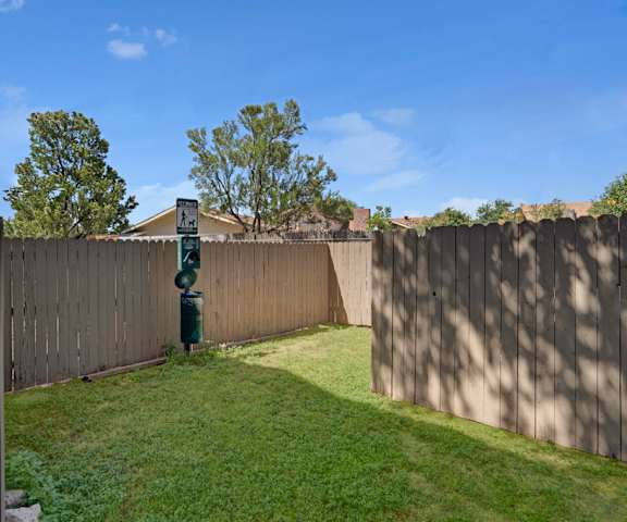 The fenced-in dog park with a dog sanitary station and grassy play area at Summertree Place Residences. 