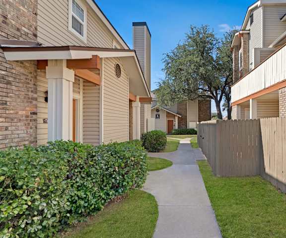 The pathways between apartment buildings with grass and bushes on each side at Summertree Place Residences. 