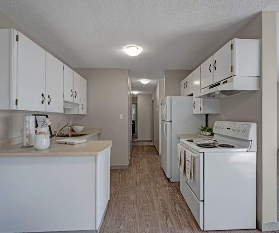 A white kitchen with white appliances and white cabinets at Cedar Gardens Apartment Homes. 