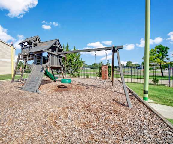 The fun, dark brown playground with swings, climbing ladders, a slide, and other fun activities at Summit Point Apartment Homes. 