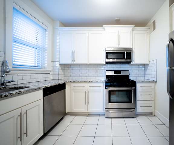 A kitchen with white cabinets and a black refrigerator.