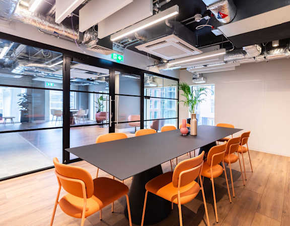 a conference room with a long table and orange chairs