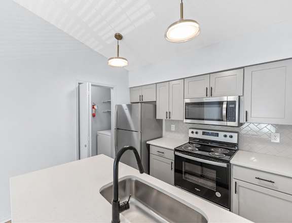 A kitchen with white cabinets and a stainless steel sink.