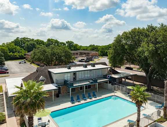 A pool surrounded by trees and a building in the background.