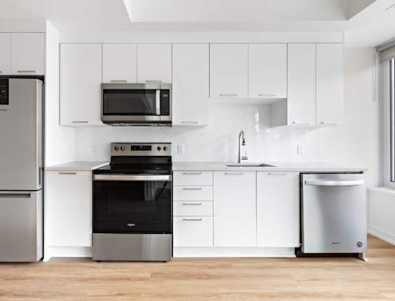 A modern kitchen with white cabinets and stainless steel appliances.