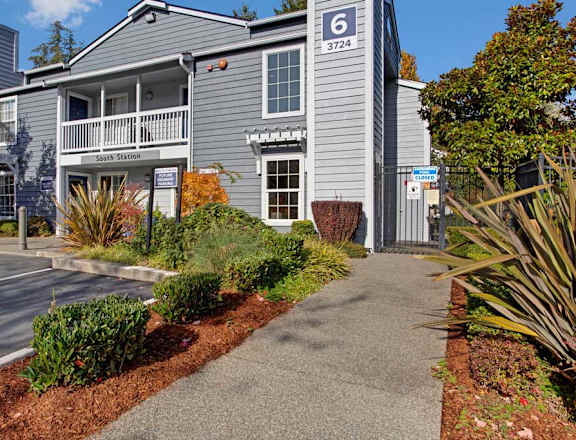 A building with the number 6 on it is surrounded by plants and trees.