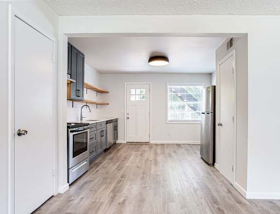 a kitchen with white walls and wood floors
