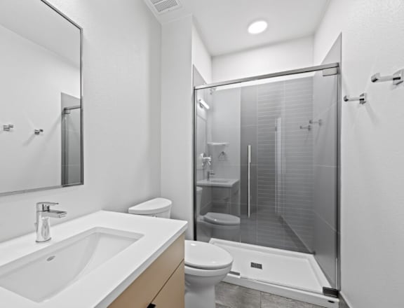 A modern bathroom with a white sink and a walk-in shower. at The Avenue Lofts Golden Apartments, Golden 80401
