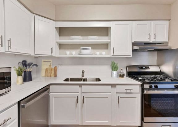 a white kitchen with stainless steel appliances and white cabinets