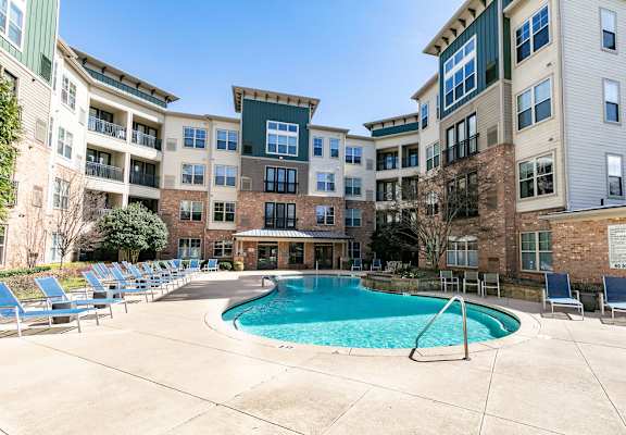 a swimming pool with chaise lounge chairs and an apartment building in the background at Westmount at Ashwood Apartments, Atlanta, GA, 30338