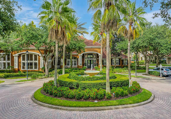A building with a landscaped front yard and palm trees.
