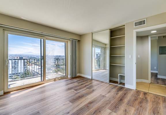 an empty living room with wood floors and a large window