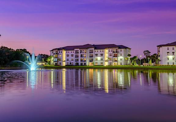 a fountain in a lake with buildings in the background at night at Inspira, Florida