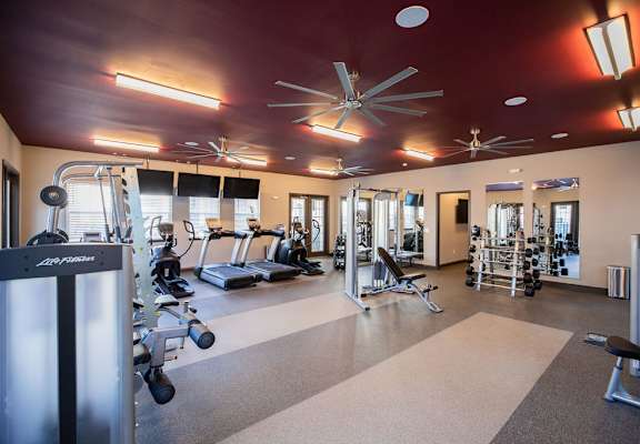 A gym with a variety of equipment including treadmills, weights, and exercise machines.