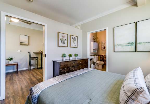 A bedroom with a large bed and a chair.