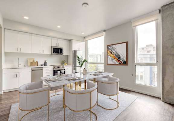 A modern kitchen with white cabinets and a dining table set for two.