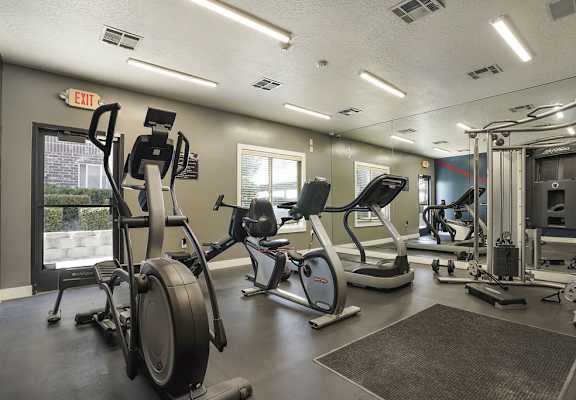 A gym with a variety of equipment including treadmills, stationary bikes, and weight machines.