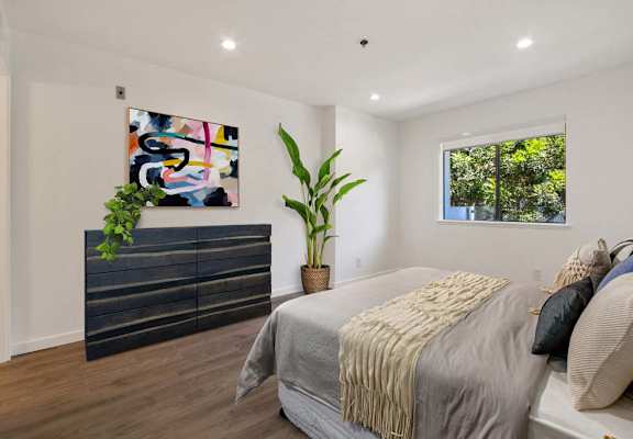 a bedroom with a bed and a dresser in front of a window