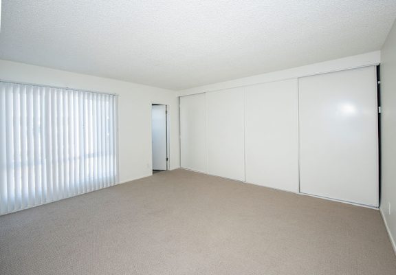 A room with white cupboards and a carpeted floor.