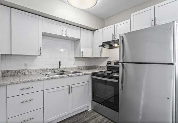 a kitchen with white cabinets and a stainless steel refrigerator