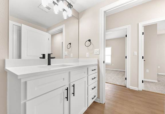 A bathroom with a white vanity and a mirror above it.