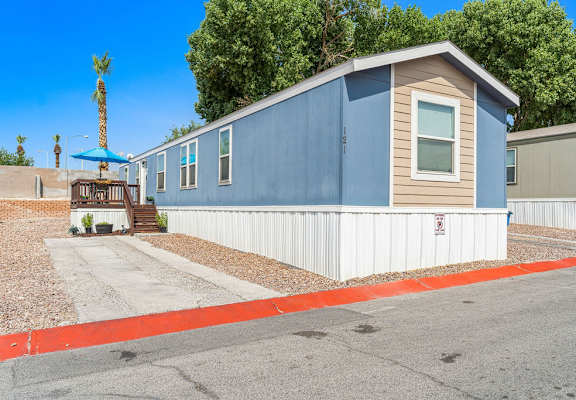 a blue and brown mobile home with a white fence in front of it